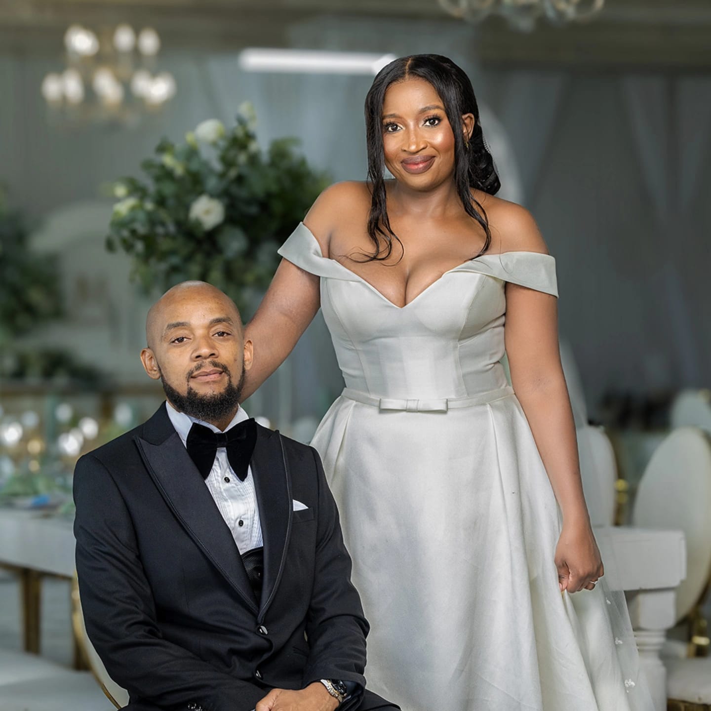 Bride and groom portrait under a chandelier, holding hands