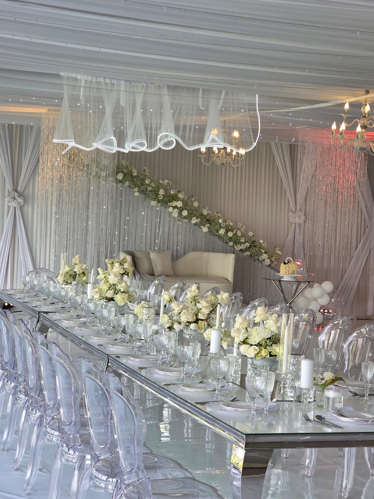 Long mirrored reception table styled with roses, candles and crystal glassware