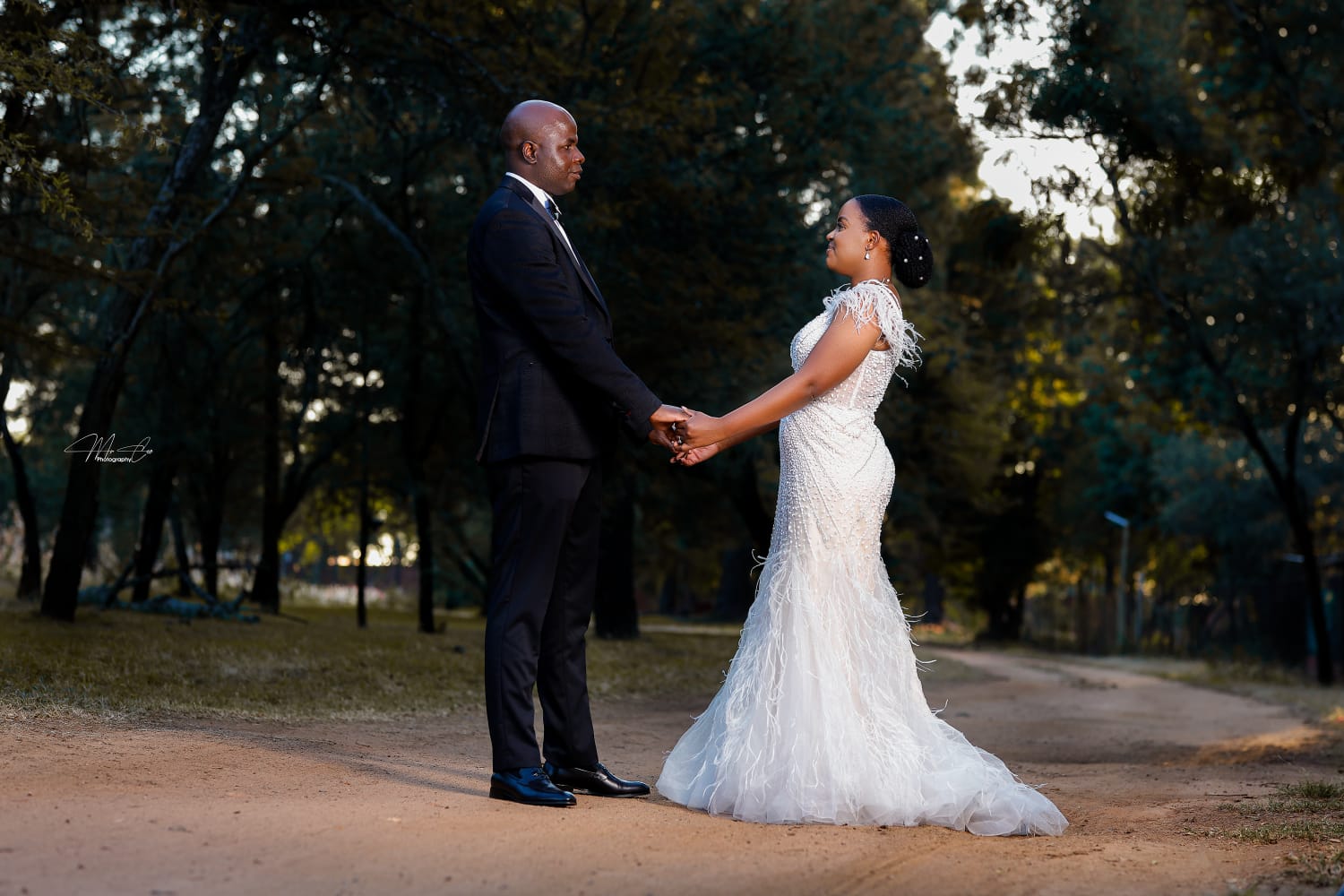 Bride and groom holding hands on a garden path at golden hour