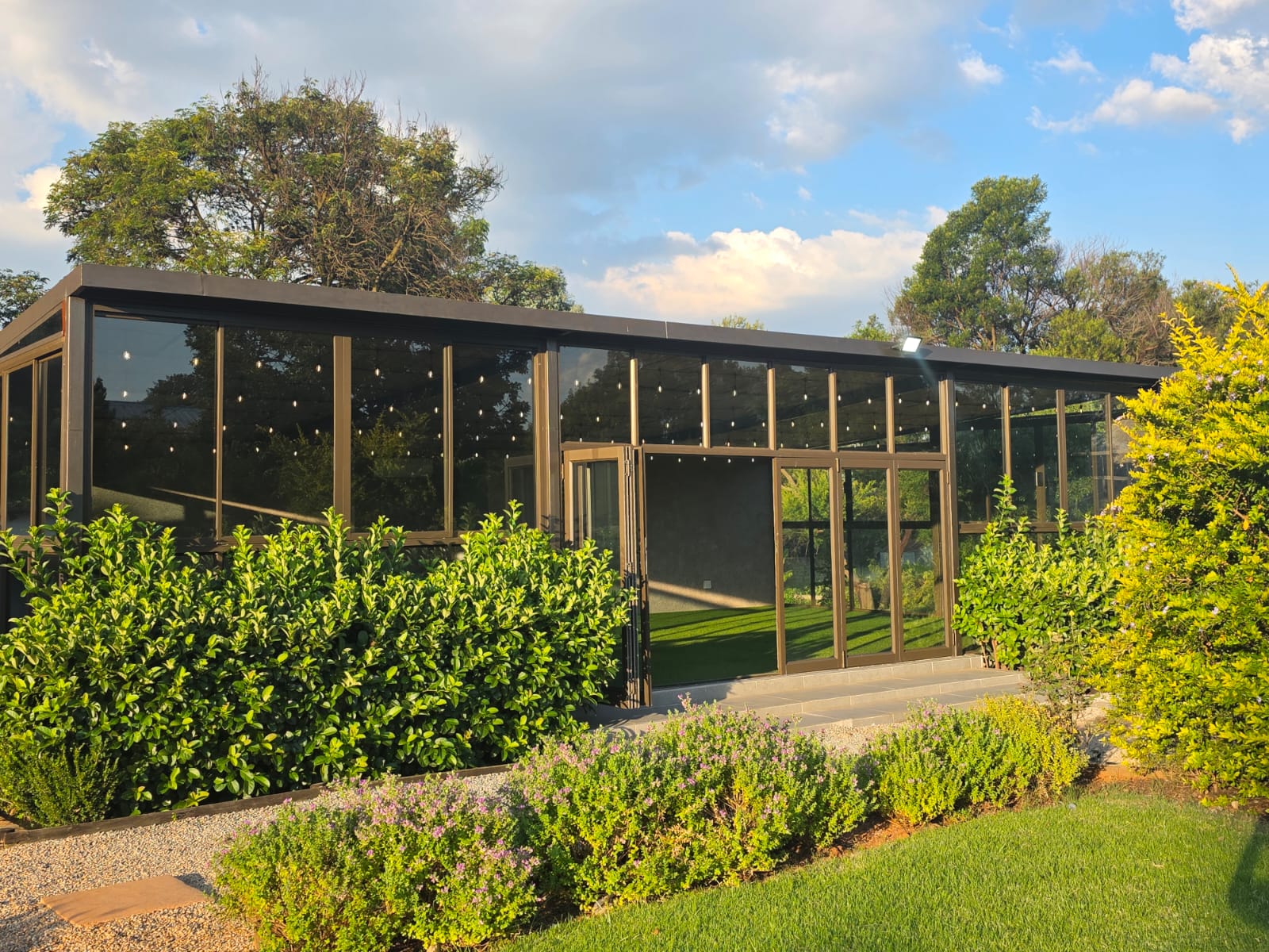 Dakalo Glass Venue at Muano Functions Venue, surrounded by manicured gardens at golden hour